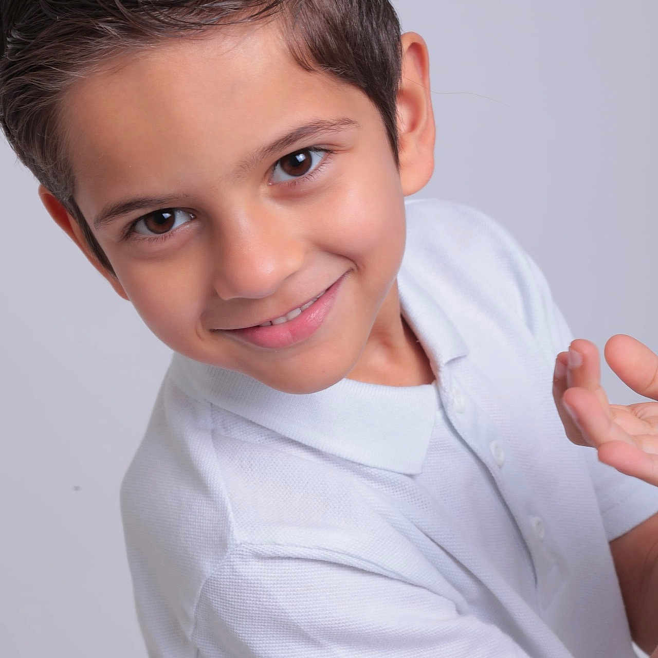 Rayan is registered to the contest to win money with this photo: boy, casual_clothing, child, cute, eyebrows, eyes, face, hands, happy, head, innocent, light_background, person, portrait, short_hair, skin, smile, studio, white_polo_shirt, young