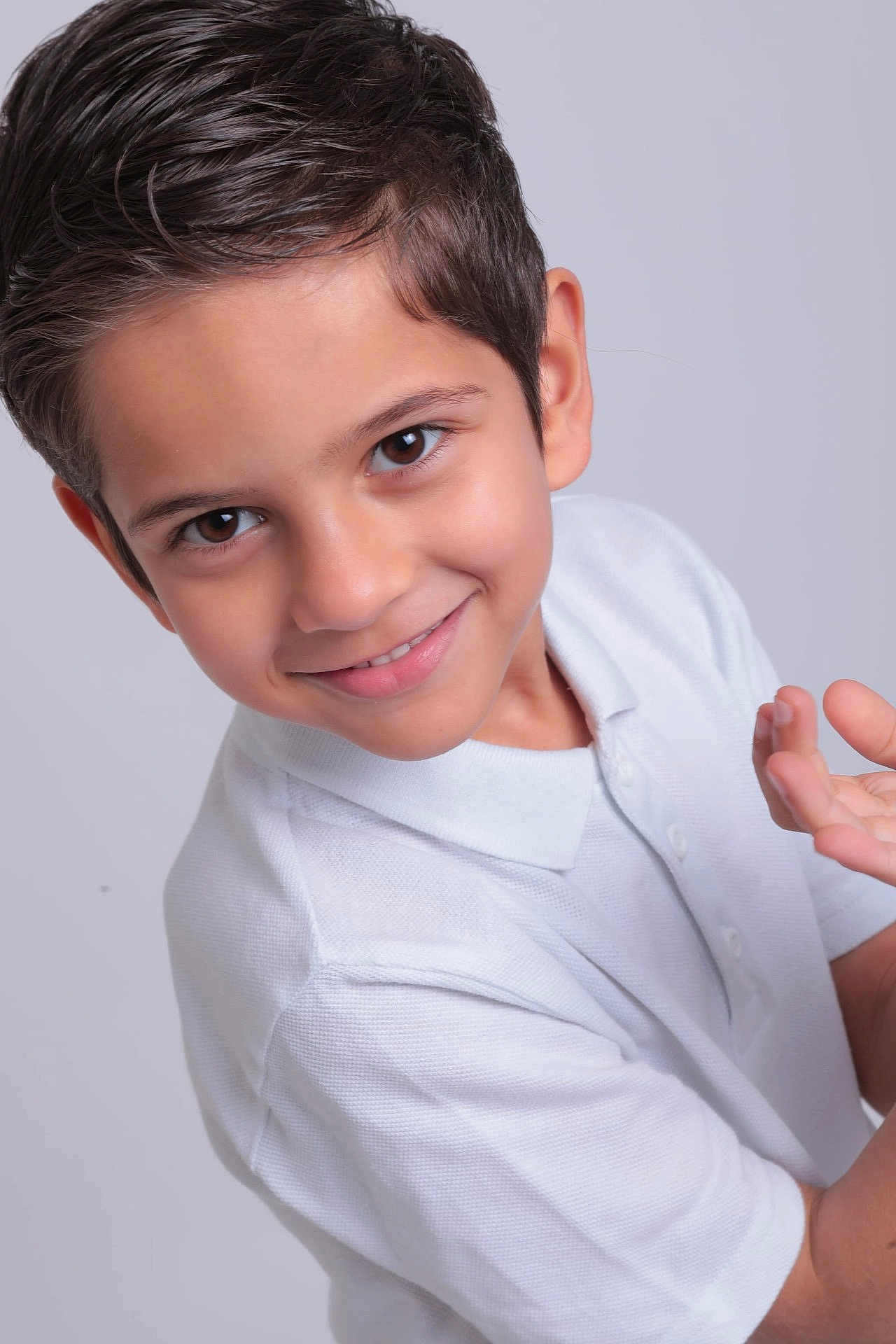 Rayan is registered to the contest to win money with this photo: child, boy, smile, face, white_polo_shirt, short_hair, portrait, studio, light_background, happy, casual_clothing, skin, eyebrows, eyes, hands, cute, young, innocent, person, head