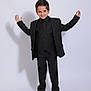 boy, child, smile, black_suit, standing, pose, shadow, studio, casual_shoes, young, portrait, confident, formal_wear, background, happy, fashion, single_person, indoors, full_length, studio_lighting
