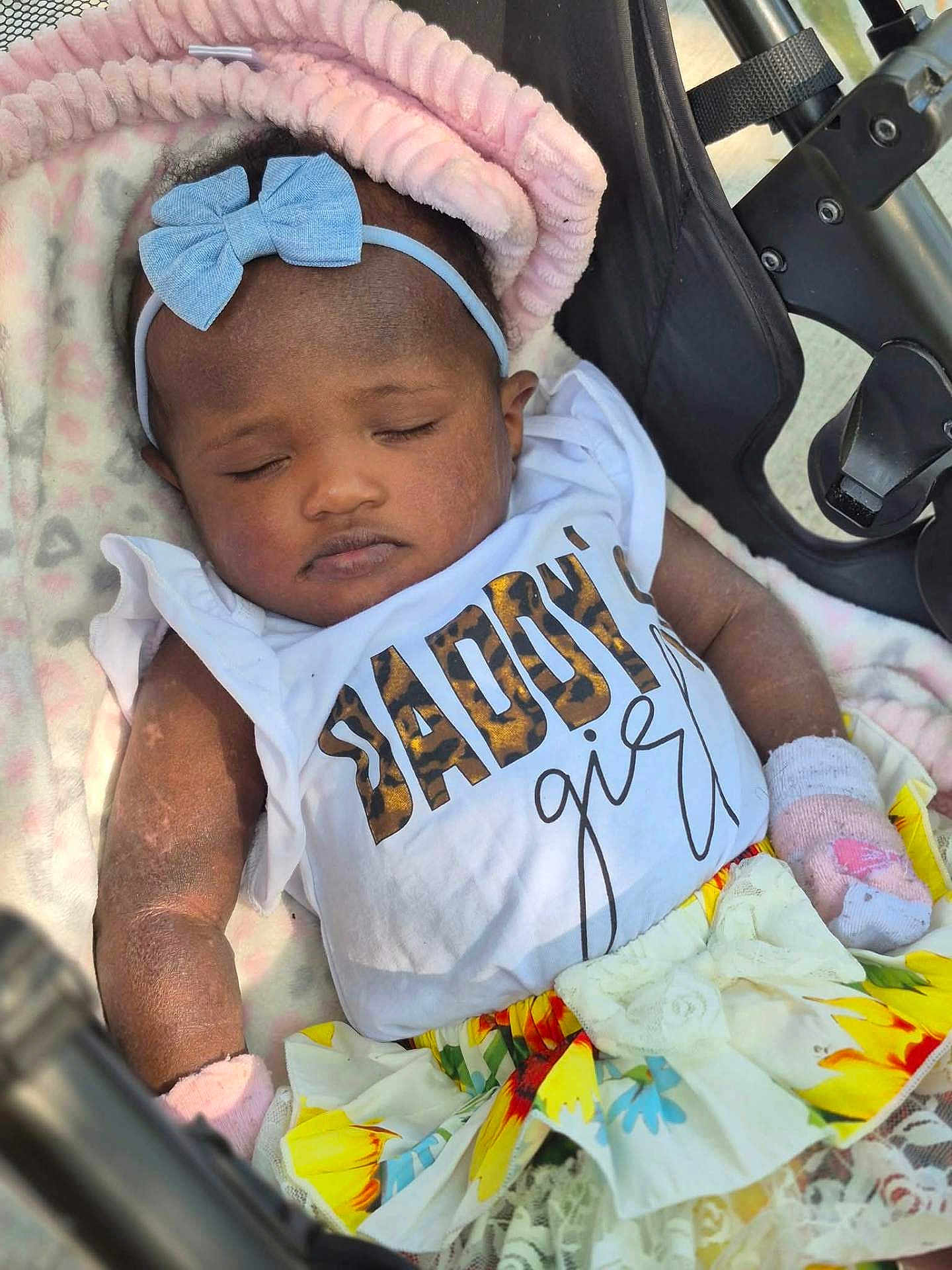 Summer is registered to the contest to win money with this photo: baby, sleeping, girl, headband, bow, blanket, stroller, clothing, skirt, flower_pattern, white_shirt, cute, infant, peaceful, child, resting, portrait, pink, soft, adorable