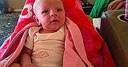 Summer joined the competition — help win amazing prizes! baby, blanket, pink, red, infant, face, tear, indoor, living_room, couch, person, clothing, cozy, curious, child, wrapped, seated, soft, warm, home