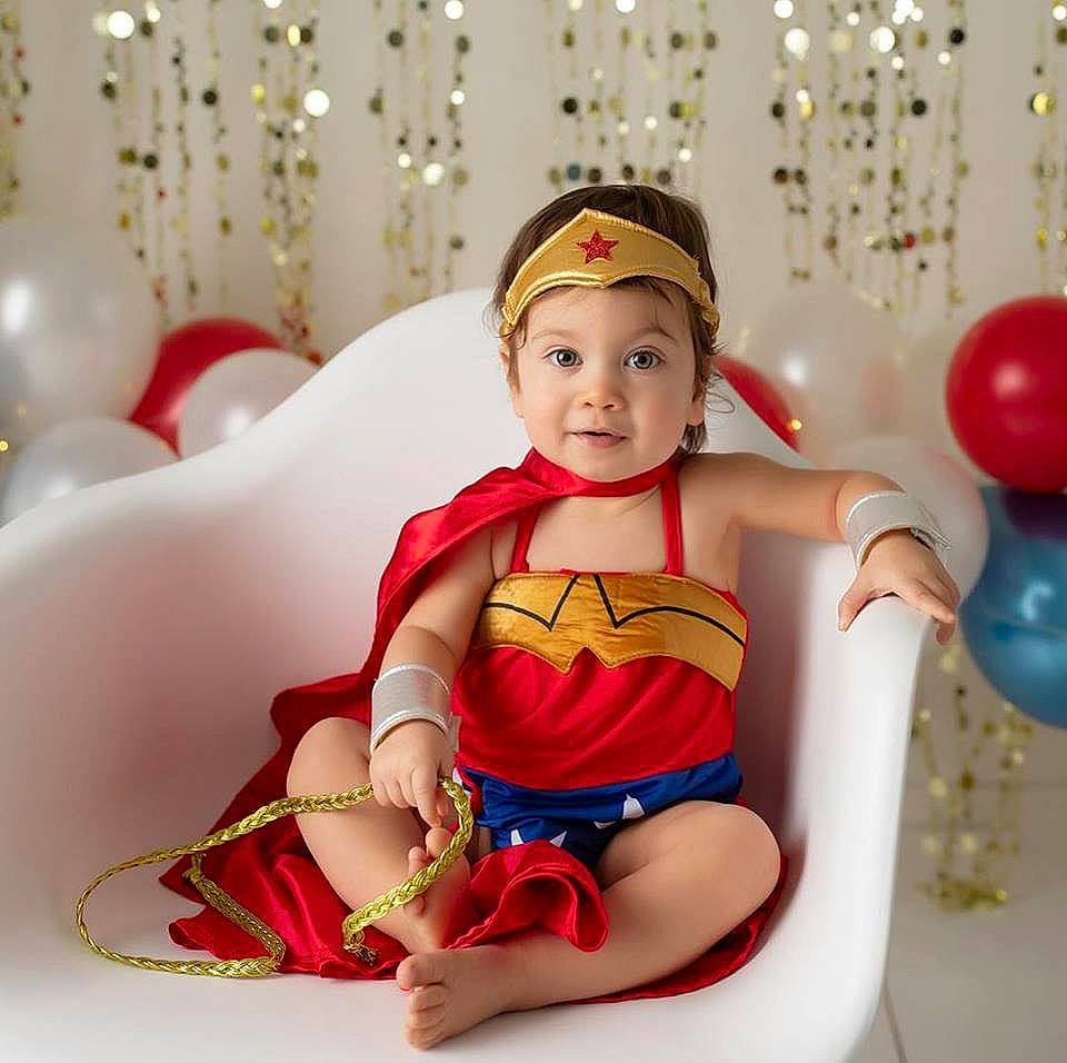 Domenica is registered to the contest to win money with this photo: arm, baby, child, child_model, costume, fictional_character, figurine, happy, headgear, leg, muscle, person, play, red, sitting, smile, superhero, thigh, toddler, trunk