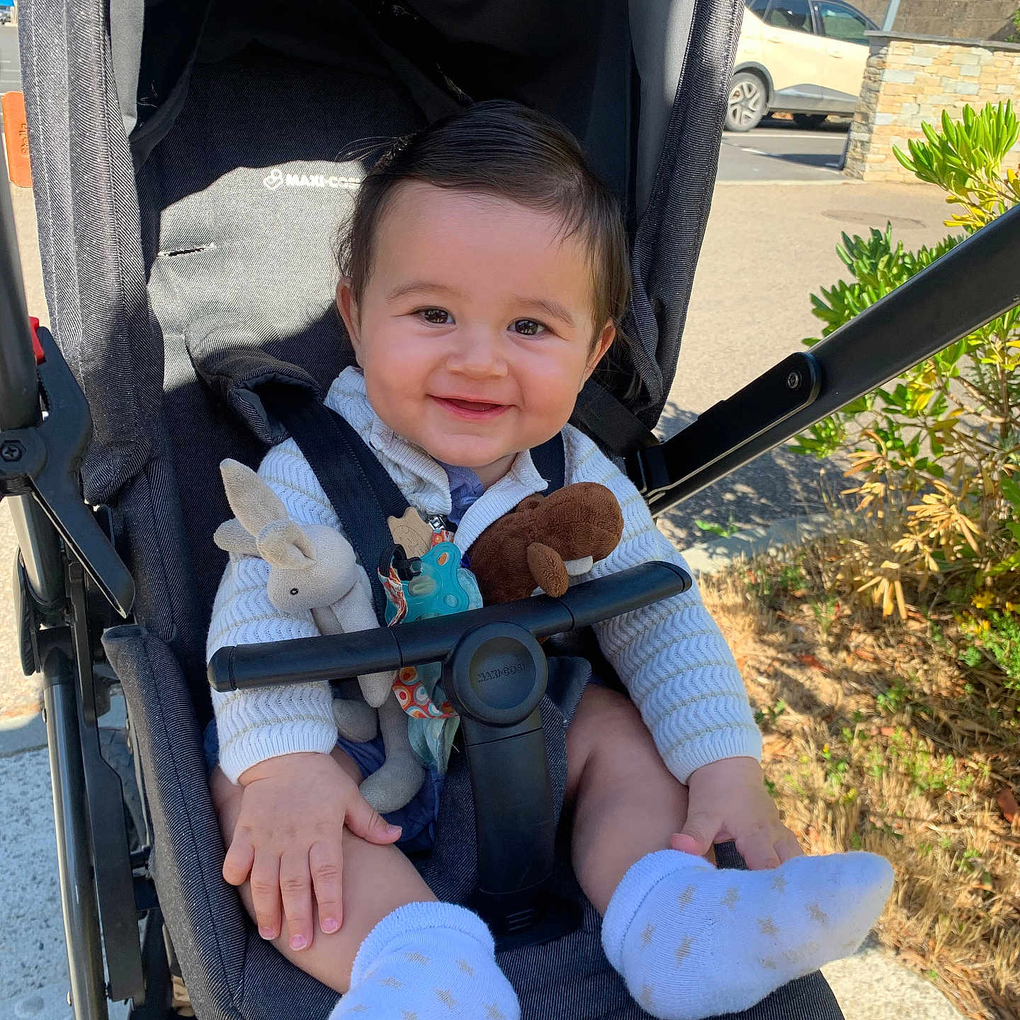 Marceau a rejoint le concours — aidez-le/la à gagner de superbes lots ! baby, baby_toys, casual, child, clothing, cute, greenery, happy, infant, nature, outdoor, parked_car, person, seat, smiling, sock, stroller, sunlight, toy, transport