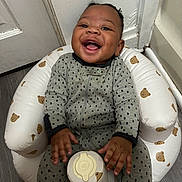 Zakai joined the competition — help win amazing prizes! baby, child, smiling, infant, seat, cushion, bear_pattern, gray_clothing, indoor, floor, happy, cute, young, person, sitting, furniture, face, home, cozy, playful
