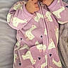 Freyja is registered to the contest to win money with this photo: baby, infant, child, portrait, lying_down, onesie, unicorn_pattern, pink_clothing, blanket, bed, indoor, cozy, face, eyes, hands, fingers, self_soothing, looking_at_camera, soft_lighting, cute