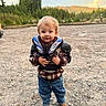 Cohen joined the competition — help win amazing prizes! child, toddler, outdoor, portrait, standing, smiling, face, blond_hair, protective_gear, motorcycle_gear, jacket, jeans, boots, gravel, mountains, forest, evergreen_trees, landscape, travel, daylight
