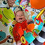 Leon joined the competition — help win amazing prizes! baby, infant, play_mat, toy, colorful, orange_clothing, smiling, happy, child, indoor, soft_toy, hanging_toys, patterned_mat, striped_toy, playtime, cute, small_child, person, fun, baby_gym