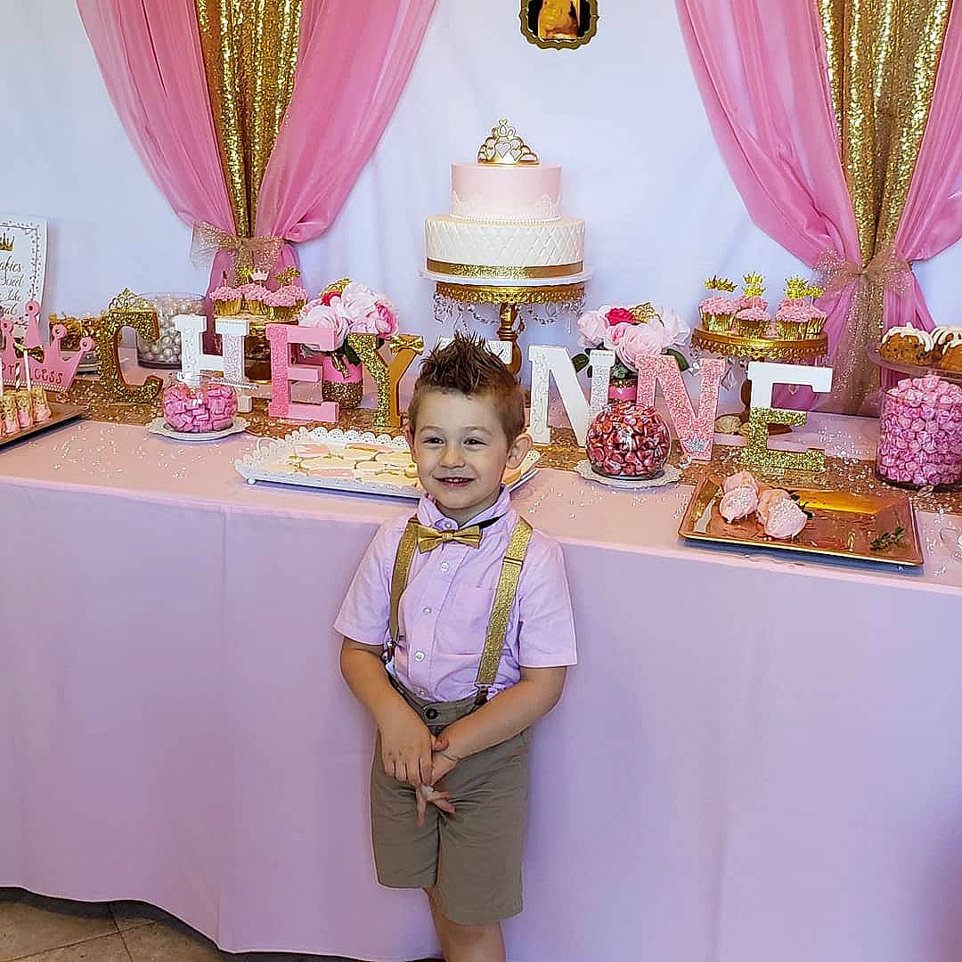 Deegan is registered to the contest to win money with this photo: birthday, ceremony, child, decoration, dress, event, function_hall, furniture, interior_design, joy, magenta, party, party_supply, peach, person, pink, purple, room, table, tableware