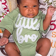 Phoenix joined the competition — help win amazing prizes! baby, infant, child, green_onesie, socks, blanket, patterned_blanket, face, expression, raised_hand, cute, newborn, portrait, lying_down, indoors, clothing, soft_texture, skin, person, young