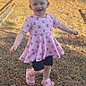 child, toddler, girl, smiling, happy, outdoor, portrait, standing, dress, pink_clothing, hair_bows, sandals, playground, gravel, sunlight, outdoor_photography, fashion, full_body, joyful, background_person