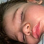 child, sleeping, face, close_up, rosy_cheeks, hair, pillow, resting, peaceful, innocence, skin, eyelashes, nose, lips, indoors, quiet, soft_light, portrait, young, relaxation