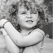 Dolly-Storm joined the competition — help win amazing prizes! child, curly_hair, black_and_white, portrait, smile, bracelet, tank_top, outdoor, expression, face, person, necklace, cute, young, arms, happy, casual_clothing, closeup, natural_light, playful