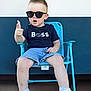 toddler, child, sunglasses, blue_chair, shorts, tshirt, white_sneakers, pointing, indoor, casual_clothing, confident, pose, person, footwear, short_hair, seat, young_child, fashion, cool, portrait