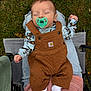 baby, pacifier, sleeping, outdoor, grass, overalls, brown_clothing, person, lap, blue_shirt, socks, stroller, hand, nature, casual, relaxation, infant, quilted, footwear, comfort