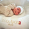 Luca is registered to the contest to win money with this photo: baby, bed, calm, child, comfort, cozy, cushion, deluxe, dockatot, face, hat, indoor, infant, newborn, person, portrait, resting, sleepwear, soft_light, striped_clothing