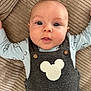 baby, infant, face, eyes, clothing, overalls, mouse_shape, blanket, texture, cute, curious, lying_down, child, portrait, button, soft, indoors, skin, head, expression