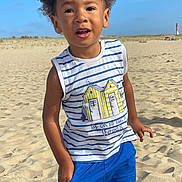 Marlon participe au concours pour gagner de l'argent avec cette photo : child, beach, sand, blue_sky, striped_shirt, blue_shorts, curly_hair, casual_pose, summer_clothing, outdoor, sunny, young_boy, standing, portrait, daytime, nature, vacation, sand_dunes, happy, exploring