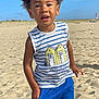 child, beach, sand, blue_sky, striped_shirt, blue_shorts, curly_hair, casual_pose, summer_clothing, outdoor, sunny, young_boy, standing, portrait, daytime, nature, vacation, sand_dunes, happy, exploring