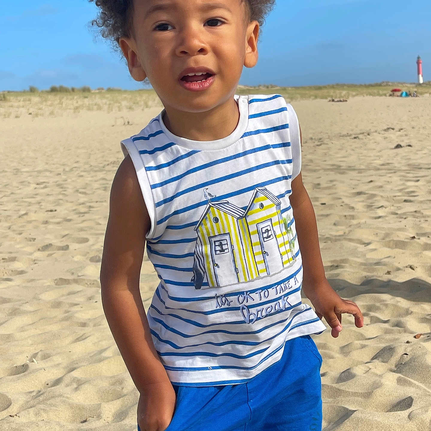 Marlon participe au concours pour gagner de l'argent avec cette photo : beach, blue_shorts, blue_sky, casual_pose, child, curly_hair, daytime, exploring, happy, nature, outdoor, portrait, sand, sand_dunes, standing, striped_shirt, summer_clothing, sunny, vacation, young_boy