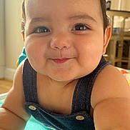 Benjamin is registered to the contest to win money with this photo: baby, child, face, smile, denim, overalls, arm, skin, hair, indoors, furniture, table, light, sunlight, cheeks, eyes, expression, portrait, closeup, cute