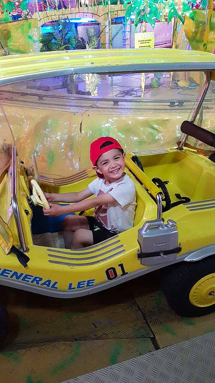 Djulian participe au concours pour gagner de l'argent avec cette photo : automotive_design, automotive_exterior, automotive_tire, bumper, car, fun, hat, headwear, helmet, hood, joy, leisure, mode_of_transport, motor_vehicle, person, recreation, riding_toy, smile, tire, toddler