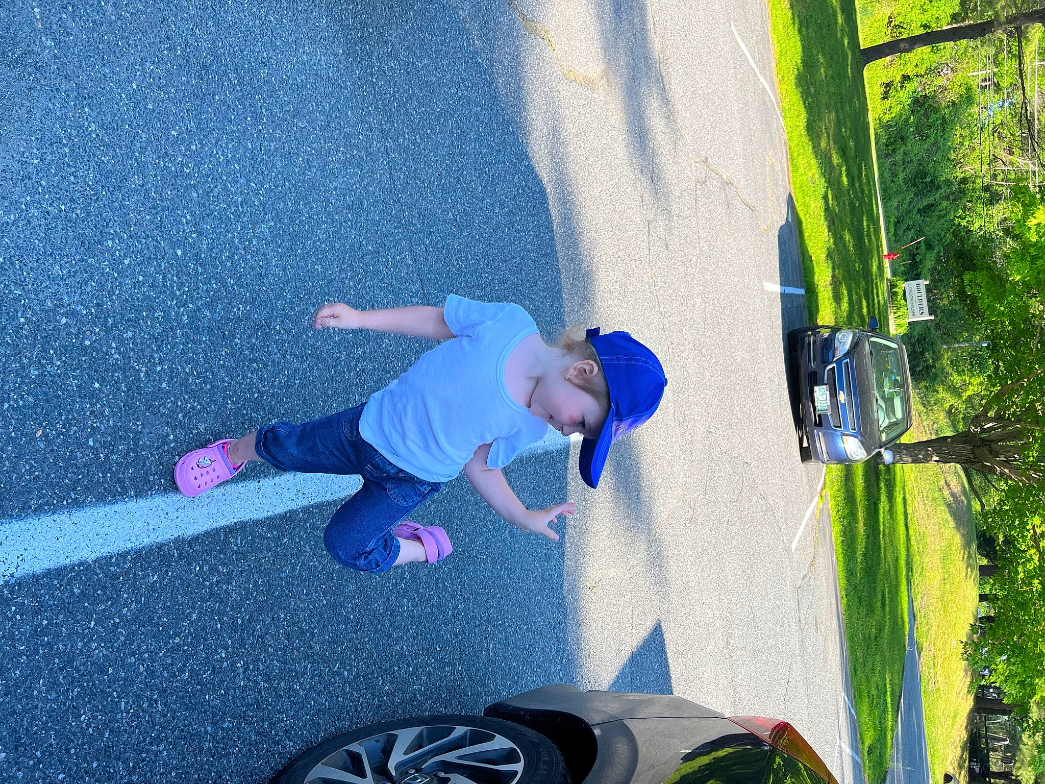 Ashlyn is registered to the contest to win money with this photo: asphalt, automotive_exterior, automotive_tire, car, electric_blue, fun, grass, headwear, leisure, light, person, plant, recreation, rolling, t_shirt, tire, toddler, tree, vehicle, vehicle_door