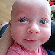Madelyn is registered to the contest to win money with this photo: baby, close_up, face, blue_eyes, pink_clothing, polka_dots, infant, cute, smile, skin, head, person, human, child, portrait, indoors, soft_light, expression, young, curious