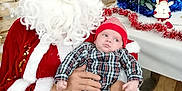 Jules participe au concours pour gagner de l'argent avec cette photo : baby, beard, celebration, chair, child, christmas_tree, festive, glasses, holiday_decorations, indoor, ornaments, person, plaid_shirt, red_hat, santa_claus, seasonal, table, tinsel, toy, winter_clothing