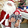 Jules participe au concours pour gagner de l'argent avec cette photo : baby, child, santa_claus, christmas_tree, holiday_decorations, tinsel, red_hat, plaid_shirt, glasses, beard, festive, indoor, person, chair, table, ornaments, toy, celebration, winter_clothing, seasonal