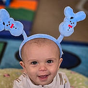 Charles is registered to the contest to win money with this photo: baby, background, blue, bunny_ears, child, clothing, colorful, comfort, cushion, cute, eyes, face, happy, headband, indoor, infant, pattern, portrait, smile, young