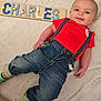 Charles joined the competition — help win amazing prizes! baby, infant, child, smile, face, wooden_letters, name_board, blanket, red_shirt, denim_jeans, suspenders, socks, lying_down, portrait, cute, hand, leg, close_up, home_interior, cozy