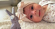 Julia a rejoint le concours — aidez-le/la à gagner de superbes lots ! baby, infant, headband, bow, blanket, ceramic_bunny, toy, soft_texture, floral_clothing, lying_down, indoors, cute, portrait, child, face, hand, curious, cozy, decor, warm_lighting