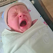 Lucas is registered to the contest to win money with this photo: newborn, baby, yawning, blanket, swaddled, infant, bed, headwear, sleepy, indoors, person, face, mouth_open, wrapped, soft, cute, small, skin, baby_hat, lying_down