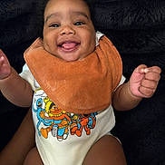 Mazi joined the competition — help win amazing prizes! baby, smiling, tongue_out, bib, onesie, sesame_street, colorful_clothing, happy, infant, cute, child, portrait, indoor, closeup, fuzzy_background, person, skin, hand, face, young