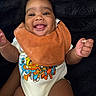 baby, smiling, tongue_out, bib, onesie, sesame_street, colorful_clothing, happy, infant, cute, child, portrait, indoor, closeup, fuzzy_background, person, skin, hand, face, young