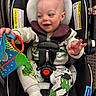 baby, car_seat, child, toy, mickey_mouse, pajamas, socks, happy, infant, indoor, seatbelt, playful, cute, smiling, childrens_toy, person, clothing, fabric, seat, comfort