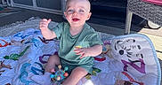 Rivers joined the competition — help win amazing prizes! baby, child, smiling, play_mat, toy, outdoor, patio, sunlight, happy, sitting, clothing, sock, colorful, animal_print, plastic_toy, furniture, grill_cover, floor, blanket, person