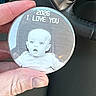 Rivers is registered to the contest to win money with this photo: hand, baby, black_and_white, round_object, text, car_interior, steering_wheel, dashboard, fingers, photo_button, portrait, surprised_face, monochrome, close_up, object_in_hand, human_skin, car_accessory, love_message, small_object, person