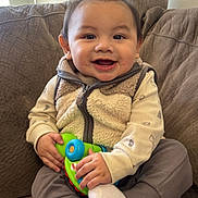 Izan Gael is registered to the contest to win money with this photo: baby, child, clothing, comfortable, couch, cozy, cute, face, furniture, hands, happy, indoor, infant, person, playful, sitting, smiling, socks, toy, vest