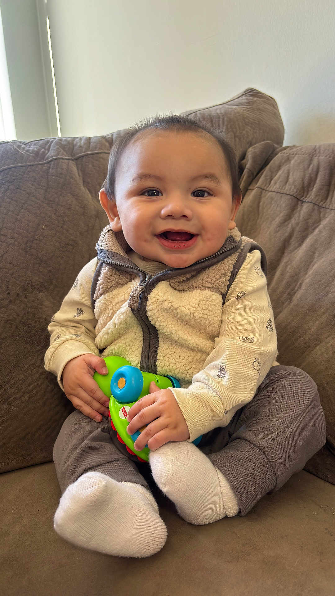 Izan Gael is registered to the contest to win money with this photo: baby, child, clothing, comfortable, couch, cozy, cute, face, furniture, hands, happy, indoor, infant, person, playful, sitting, smiling, socks, toy, vest