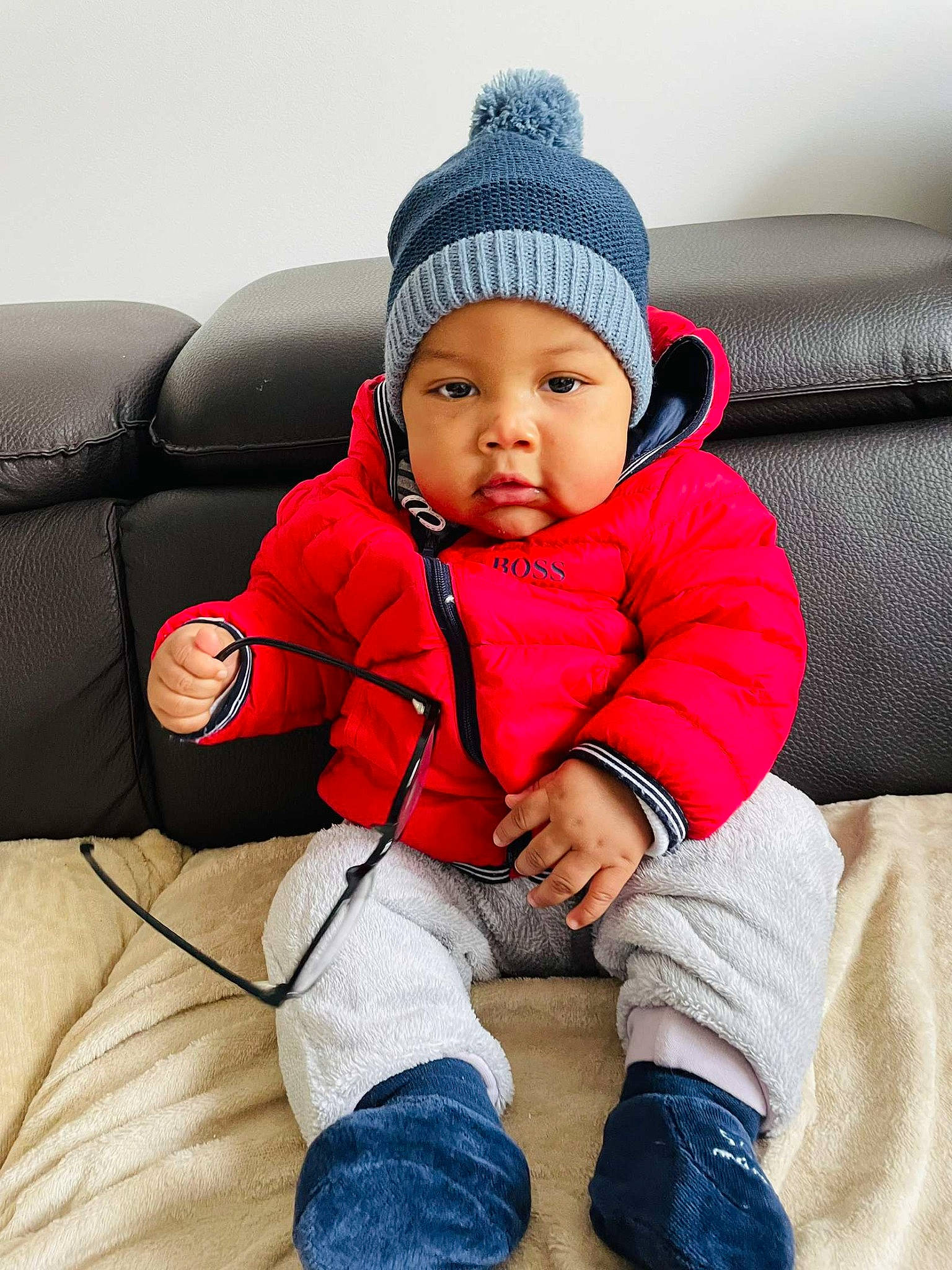 Evan participe au concours pour gagner de l'argent avec cette photo : baby, baby_toddler_clothing, cap, cheek, child, comfort, couch, electric_blue, eye, flooring, happy, head, headwear, human_body, leisure, person, sitting, sleeve, toddler, travel