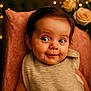 Scarlett is registered to the contest to win money with this photo: baby, infant, smile, face, eyes, bib, pink_cushion, roses, flowers, bokeh, portrait, closeup, cute, child, happy, indoors, warm_lighting, soft_texture, skin, hair