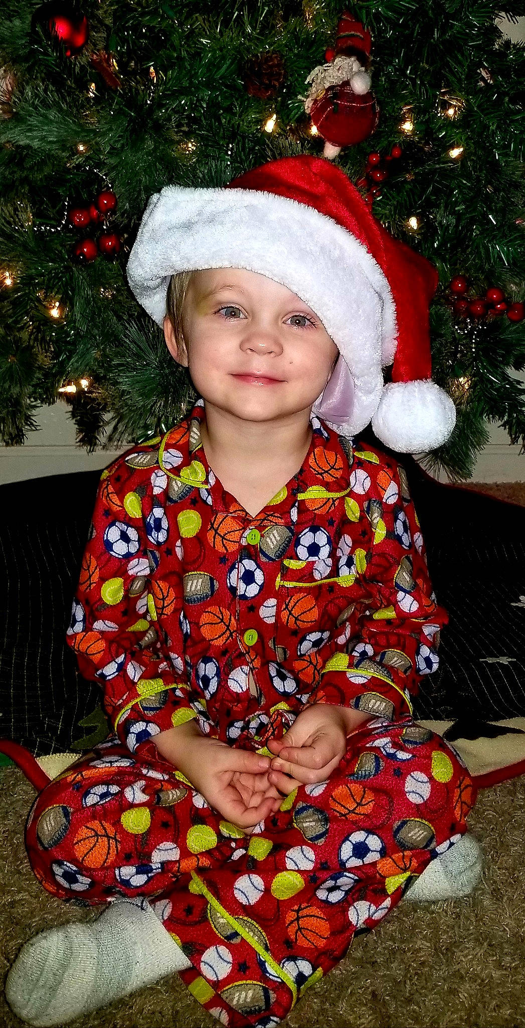 Owen is registered to the contest to win money with this photo: child, christmas, christmas_decoration, christmas_eve, christmas_ornament, christmas_tree, event, fictional_character, headwear, holiday, person, smile, toddler