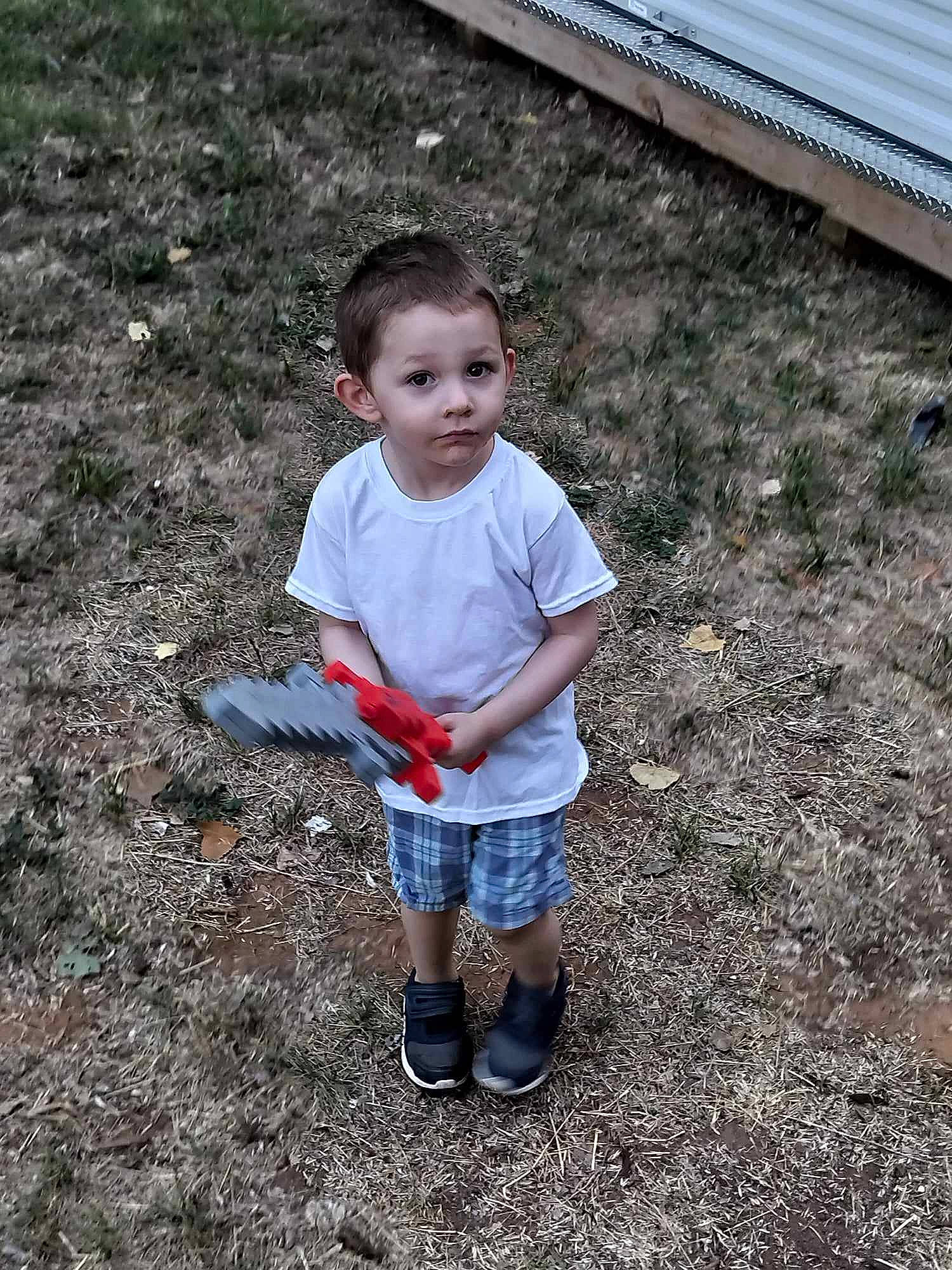 Lincoln is registered to the contest to win money with this photo: asphalt, baby_toddler_clothing, child, concrete, fun, grass, human_leg, landscape, people_in_nature, person, play, road_surface, shorts, sitting, soil, t_shirt, toddler, vacation, yard