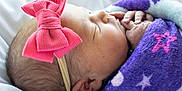 Josie is registered to the contest to win money with this photo: newborn, baby, sleeping, blanket, purple, star_pattern, pink_bow, headband, closeup, face, hand, skin, cute, infant, resting, soft, cozy, child, portrait, peaceful