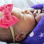 newborn, baby, sleeping, blanket, purple, star_pattern, pink_bow, headband, closeup, face, hand, skin, cute, infant, resting, soft, cozy, child, portrait, peaceful