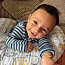 animal_print, baby, bright_eyes, child, couch, cozy, cushion, cute, face, happy, home, indoors, infant, person, pillow, portrait, resting, smiling, striped_clothing, young_child