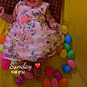 Rubi joined the competition — help win amazing prizes! baby, bright_colors, celebration, child, clothing, colorful_eggs, cushion, cute, face, floral_dress, happy, indoors, infant, laying_down, person, playful, portrait, smiling, toddler, yellow_background