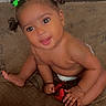 baby, barefoot, child, curious, cute, diaper, face, floor_mat, green, hair_clips, happy, indoors, looking_up, playful, portrait, red_bow, sitting, skin, smiling, young_child