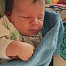 newborn, baby, sleeping, blanket, blue_blanket, infant, wrapped, hand, face, closed_eyes, cozy, soft_texture, indoors, colorful_background, patterned_surface, peaceful, resting, child, person, portrait
